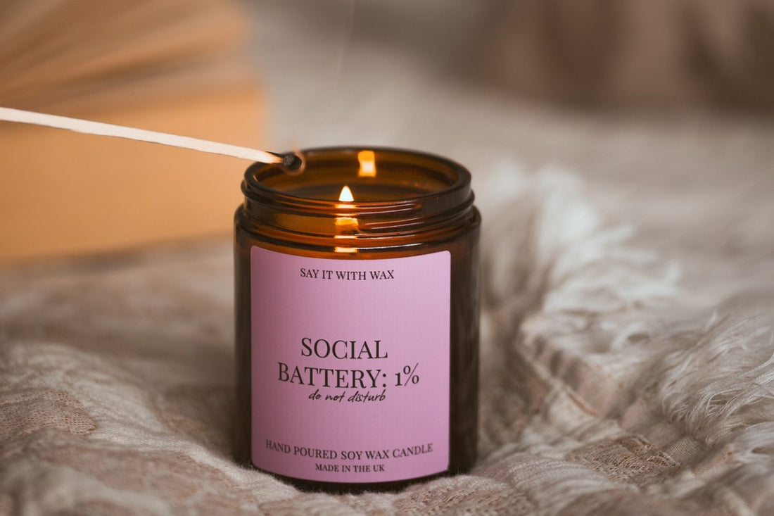 Social Battery: 1% soy candle being lit with a match on a soft knitted blanket, for the Christmas Gifts for Introverts blog post.