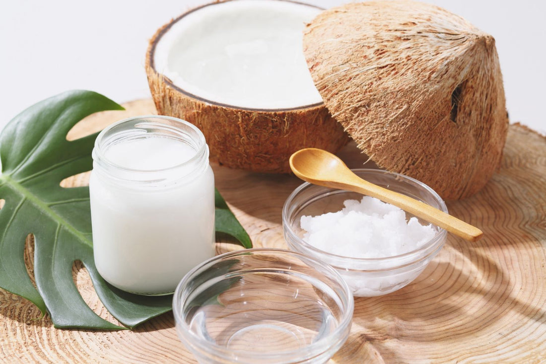 Fresh coconut halves with a jar and bowl of coconut wax, used to compare coconut wax vs soy wax for candle making