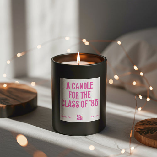 A Candle for the Class of ’85 soy wax candle in matte black glass jar with pink label and ash wooden lid, funny 40th birthday and reunion gift