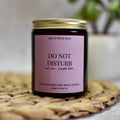 Do Not Disturb Candle with a purple label on a woven mat