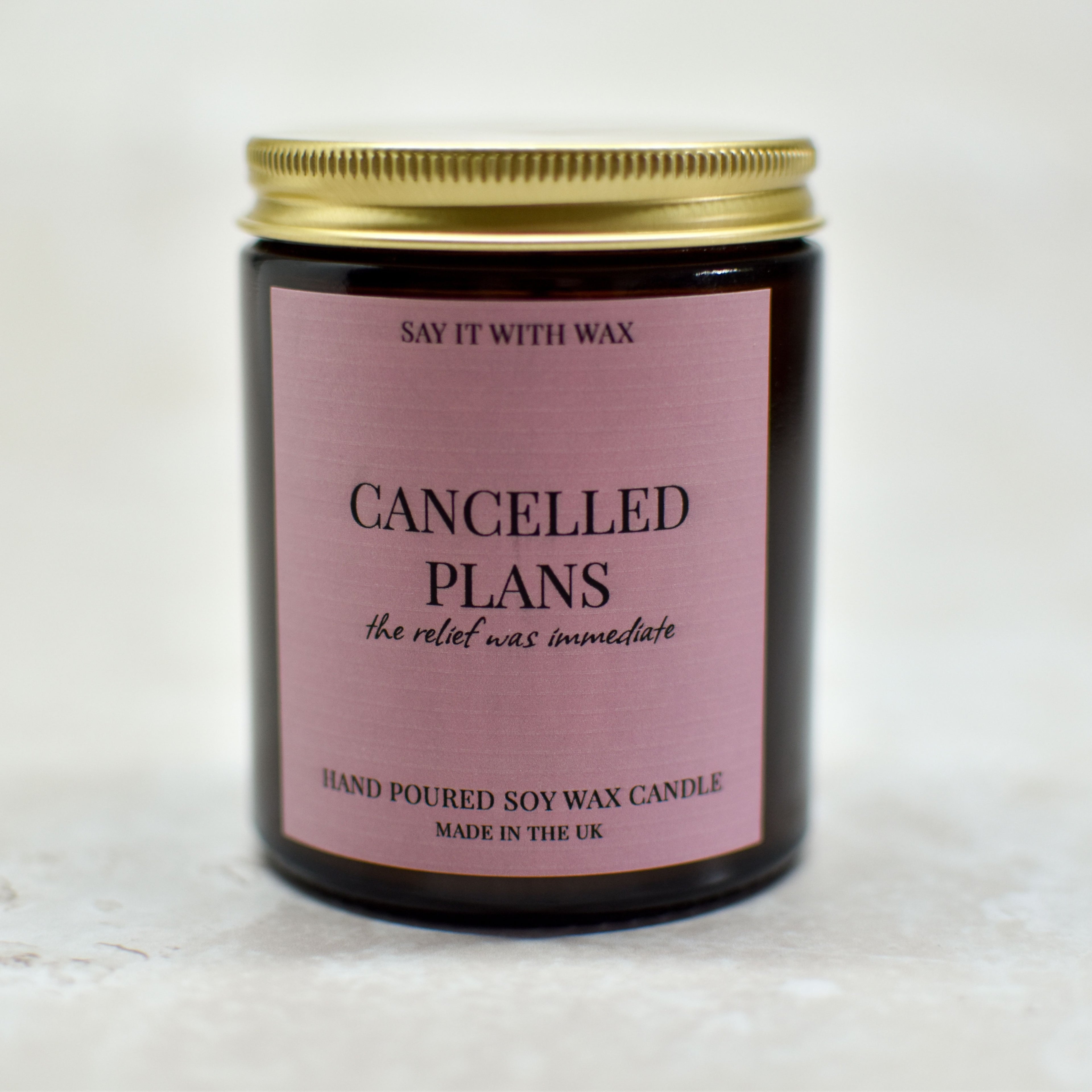 Candle with a pink label with the text cancelled plans, the relief was immediate on a white background