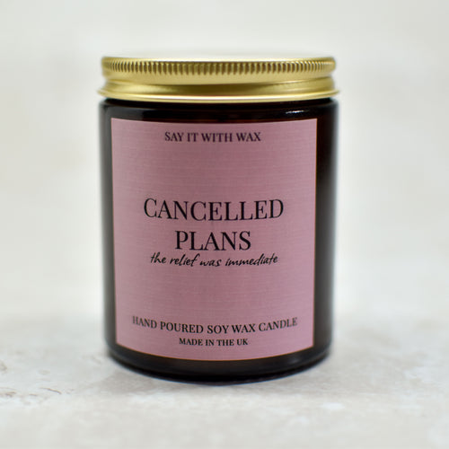 Candle with a pink label with the text cancelled plans, the relief was immediate on a white background