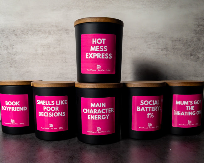 Row of black candles with pink labels on a gray surface